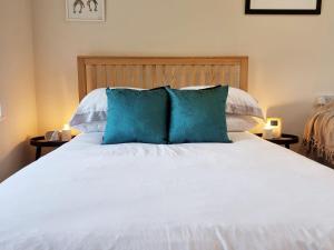 a bed with two blue pillows on top of it at The Piggery in Camerton