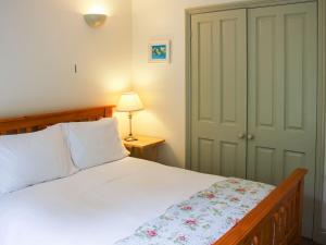 a bedroom with a bed and a lamp and a door at Willows Barn in Clenchwarton
