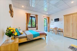 a bedroom with a bed and a table with a vase of flowers at Alley Garden Homestay Hoi An in Hoi An