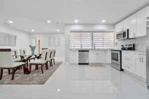 una cucina con mobili bianchi, tavolo e sedie di Beautiful & Peaceful 4 Bedroom Home With a Pool a Sunrise