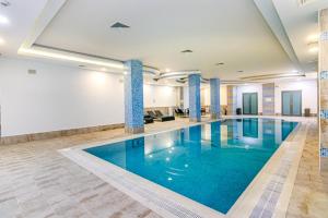 a large pool with blue water in a building at İsr Baku Hotel apartment with a pool in Baku