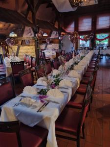 eine Reihe von Tischen mit weißen Tischdecken und Blumen in der Unterkunft Hotel Da Gianni GmbH in Oranienburg