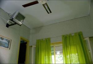 a room with a tv and a window with yellow curtains at Hotel Danubio in Villa Gesell