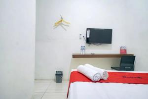 a bedroom with a bed and a tv on the wall at RedDoorz near Ekowisata Mangrove Belawan in Belawan