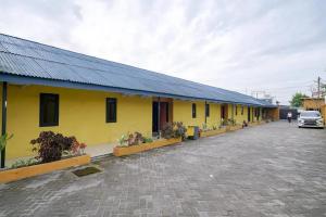 a yellow building with potted plants in a parking lot at RedDoorz near Ekowisata Mangrove Belawan in Belawan