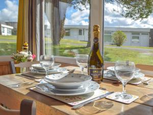 a table with a bottle of wine and plates and glasses at Ty Haf in Roch