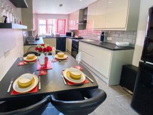una cocina con mesa y sillas y una cocina con armarios blancos. en Thistle Dew en Great Yarmouth