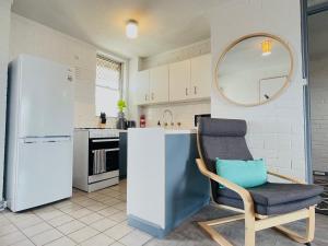 a kitchen with a chair and a white refrigerator at Port Vista - Central Fremantle Apartment in Fremantle