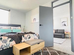 a bedroom with a bed and a room with a couch at Port Vista - Central Fremantle Apartment in Fremantle