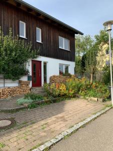 une maison avec une porte rouge et quelques fleurs dans l'établissement Schöne Wohnung in der Nähe von Schwäbisch Hall, à Rieden