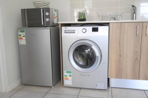 a kitchen with a washing machine and a microwave at The Parks Airport Apartment in Boksburg