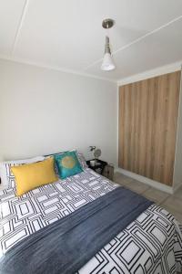 a bedroom with a bed with a yellow and blue blanket at The Parks Airport Apartment in Boksburg