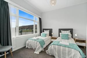 two beds in a room with a window at Lake Dunstan Cottage - Cromwell Holiday Home in Cromwell