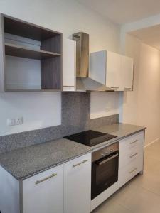 a kitchen with white cabinets and a stove top oven at Elegant 1-bedroom apartment with close amenities in Quatre Bornes