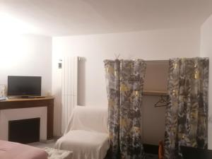 a room with a bed and a tv and curtains at Chambre 23m2 avec jardin Wi-Fi gratuit Saint-Girons in Saint-Girons