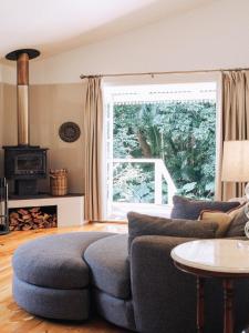 uma sala de estar com um sofá e uma grande janela em Romantic Cottage, Tamborine Mountain em Mount Tamborine