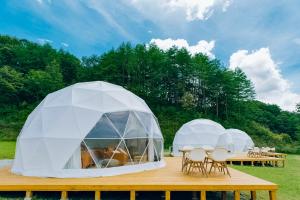 two domed tents with tables and chairs on a deck at 温泉グランピングWooods芸北 