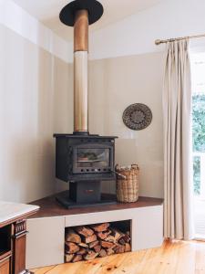 una estufa en una cocina con una pila de troncos en Romantic Cottage, Tamborine Mountain en Mount Tamborine