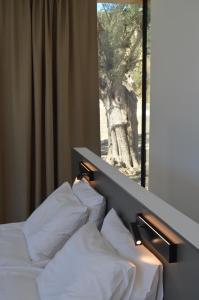 Cette chambre comprend un lit avec des oreillers blancs et une fenêtre. dans l'établissement O Mikros Kosmos Hotel Resort - Adults Only, à Sívas