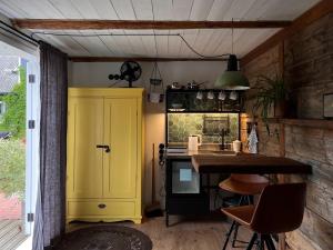a kitchen with a yellow cabinet and a table at Pāvilostas Šīfermāja in Pāvilosta