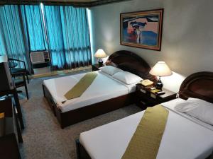 a hotel room with two beds and a table and chairs at Holiday Plaza Hotel - Cebu in Cebu City +37 photos