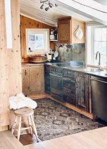 una cocina con armarios de madera, taburete y fregadero en Vasethytta - cabin with a lovely view en Brujordet