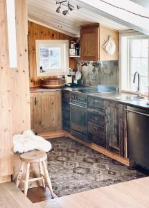a kitchen with wooden cabinets and a stool and a sink at Vasethytta - cabin with a lovely view in Brujordet