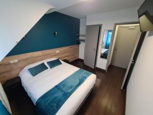 sypialnia z dużym łóżkiem i niebieską ścianą w obiekcie Berry Hôtel La Châtre w mieście La Châtre