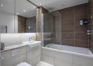 y baño con bañera, lavamanos y ducha. en Unique Sea View Penthouse with Hot Tub en Brighton & Hove