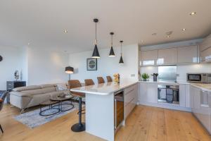 cocina y sala de estar con armarios blancos y sofá en Unique Sea View Penthouse with Hot Tub en Brighton & Hove