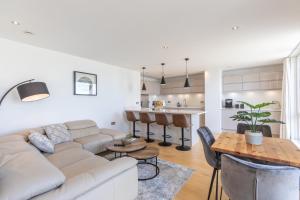 ein Wohnzimmer mit einem Sofa und einem Tisch sowie eine Küche in der Unterkunft Unique Sea View Penthouse with Hot Tub in Brighton & Hove
