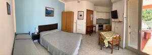 a bedroom with two beds and a table and a kitchen at Appartamento Vacanza Villetta Fichera in Gioiosa Marea