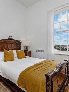 a bedroom with a large bed with yellow pillows and a window at Annesley House in Portland