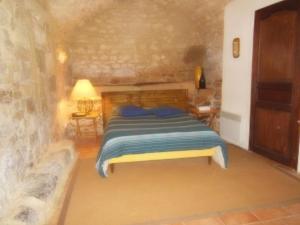 a bedroom with a bed and a stone wall at La Migrane in Villevieille