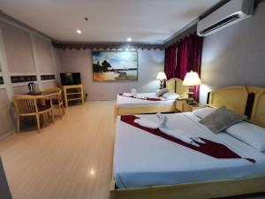 a hotel room with two beds and a table at Holiday Plaza Hotel - Cebu in Cebu City