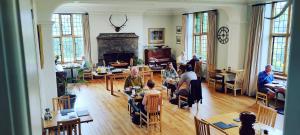 un grupo de personas sentadas en mesas en una sala de estar en Luxury Bed And Breakfast at Bossington Hall in Exmoor, Somerset, en Porlock
