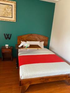 Hotel Wilson Upala في Upala: غرفة نوم بسرير وبطانية حمراء وبيضاء