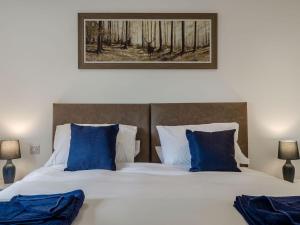 um quarto com uma cama grande e almofadas azuis em Bramley Lodge - Uk38384 em Lyonshall