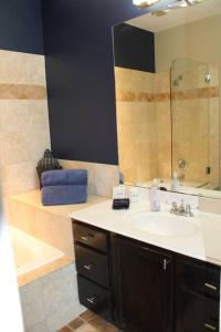 a bathroom with a sink and a mirror and a tub at Enjoy Our Ocean Oasis in Galveston