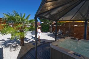 Una niña está parada junto a un jacuzzi. en Logis Hôtel Centrotel et Spa Bulles d'Allier, en Montmarault