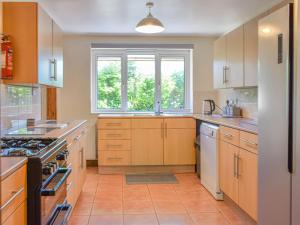 a kitchen with wooden cabinets and a window at Gladys Orchard-uk38933 in Porthcurno