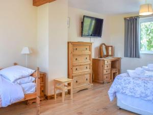 a bedroom with a bed and a dresser and a tv at Gladys Orchard-uk38933 in Porthcurno