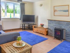 a living room with a fireplace and a tv at Gladys Orchard-uk38933 in Porthcurno