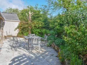 a patio with a table and chairs in a garden at Gladys Orchard-uk38933 in Porthcurno