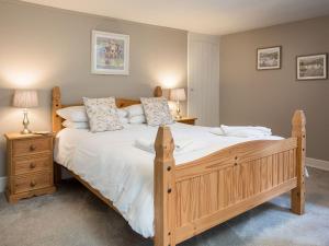 a bedroom with a large wooden bed with white sheets and pillows at Stephenson Cottage - Uk38153 in Newton