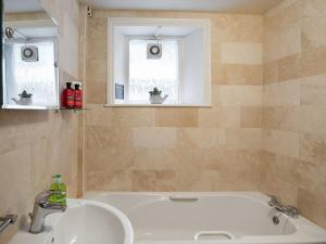 a bathroom with a tub and a sink and two windows at Stephenson Cottage - Uk38153 in Newton