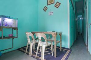 uma mesa e cadeiras num quarto com uma parede azul em SPOT ON 91732 Rani Homestay Syariah em Jodoh