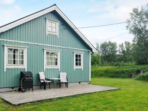 uma casa verde com duas cadeiras e um grelhador em Holiday home Tranøy em Tranøya