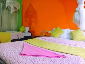 Hotel Butterfly , Sauraha , Chitwan في سوراها: غرفة نوم بسريرين وجدار برتقالي