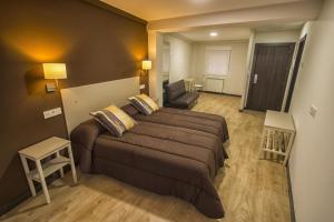 a bedroom with a large bed and a living room at Hostal Elvira in Aranda de Duero